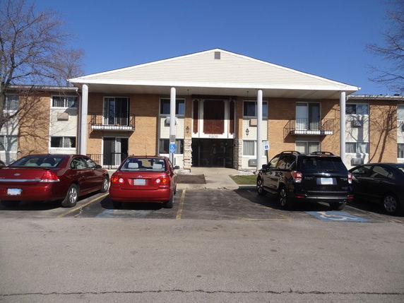 Front view of a two-story building with multiple units and parking area.