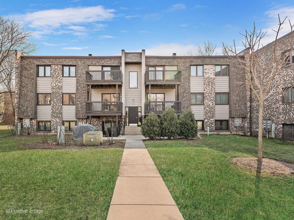 Front view of a multi-story residential building with balconies and brick facade.
