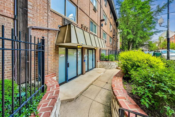 Entrance of a brick multi-story building with glass doors and an awning.