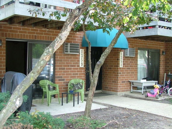 Ground floor view of a brick building with blue awnings and outdoor seating.