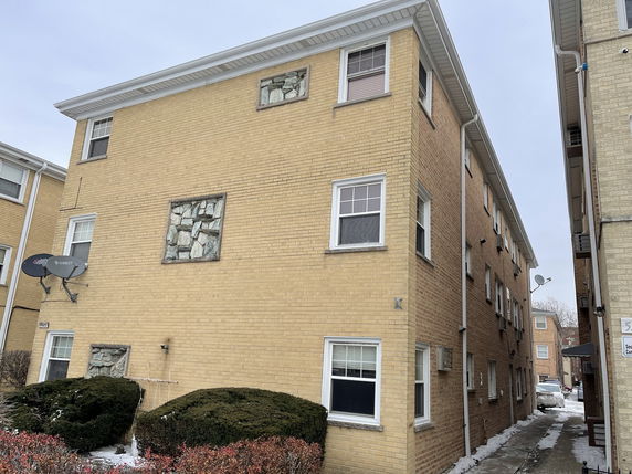 Front view of a three-story brick apartment building with rectangular windows.