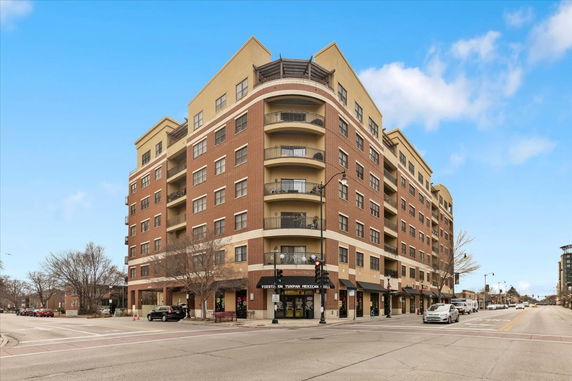 Front view of a multi-story brick and stucco building at a street corner.