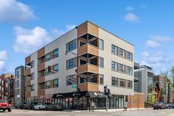 Front view of a multi-story commercial building with large windows and ground floor shops.