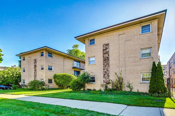Front view of two multi-story apartment buildings with flat roofs and brick exteriors.