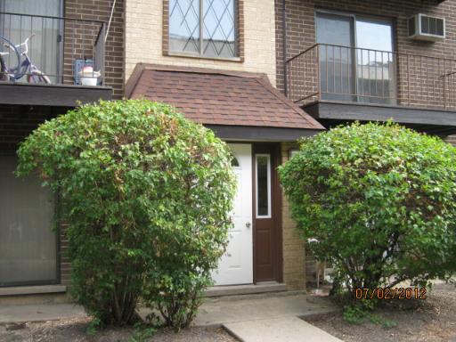 Front view of a two-story house with a brown brick facade and small entrance.