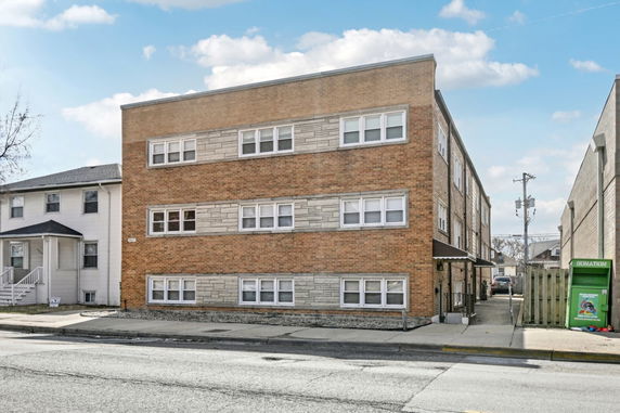 Front view of a three-story brick apartment building with multiple windows.