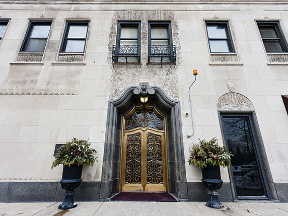 Front view of a building entrance with ornate doors and decorative stonework.