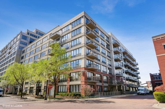 Front view of a multi-story apartment building with balconies and large windows.