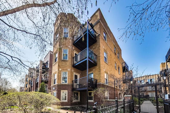 Front view of a multi-story brick apartment building with balconies.