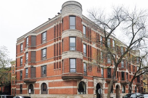 Front view of a multi-story brick apartment building with ornate architectural details.