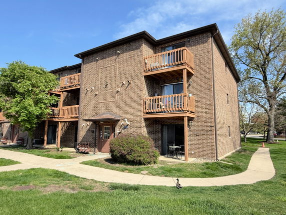 Front view of a three-story brick apartment building with balconies.