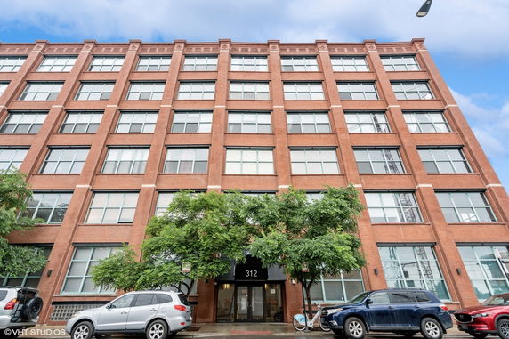 Front view of a multi-story brick building with large windows and a central entrance.