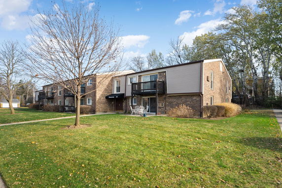 Front view of a two-story residential building with balconies and brick exterior.