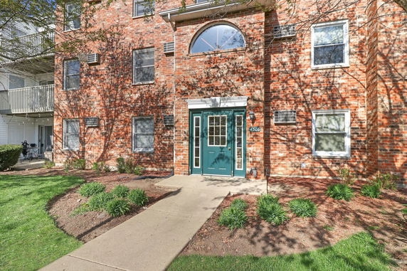 Front view of a brick apartment building with multiple windows and a green door.
