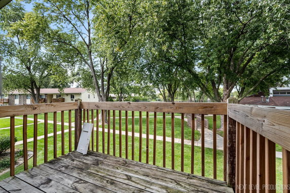 View from a wooden deck overlooking a grassy area with pathways and trees.