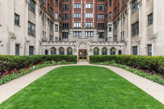 Front view of a multi-story building with arched entrance and landscaped courtyard.
