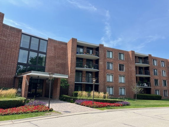 Front view of a multi-story brick apartment building with balconies.
