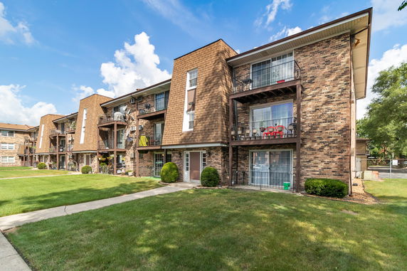 Front view of a multi-story apartment building with brick facade and balconies.