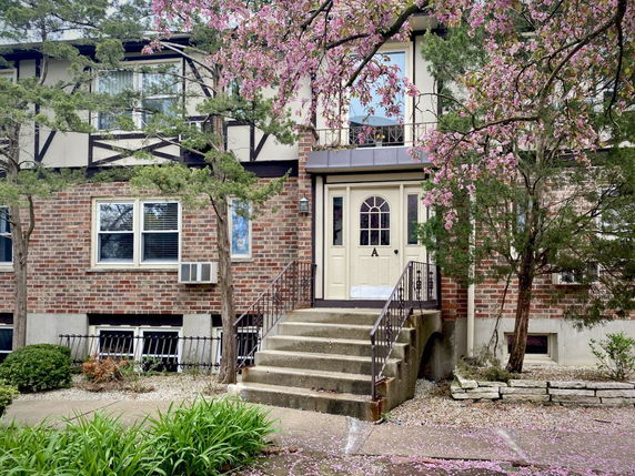 Front view of a two-story brick house with a staircase leading to the entrance.
