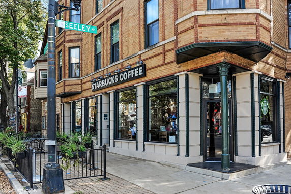 Front view of a corner Starbucks Coffee building with large windows and brick exterior.