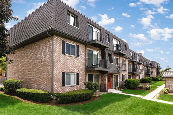 Front view of a multi-story brick apartment building with small balconies.