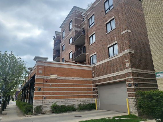 Front view of a multi-story brick apartment building with balconies.