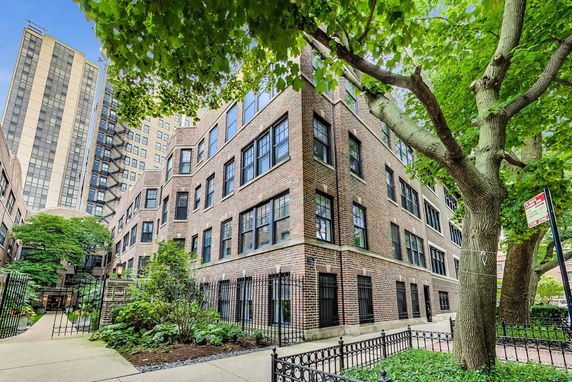 Front view of a multi-story brick building with numerous windows and a gated entrance.