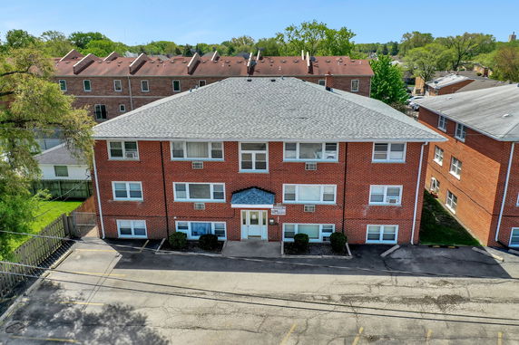 Front view of a brick three-story apartment building with a gabled roof.