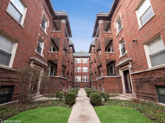 Front view of a multi-story brick apartment building with balconies.