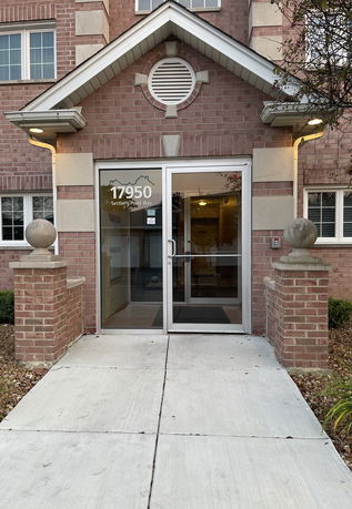 Front view of a brick building entrance with glass doors.