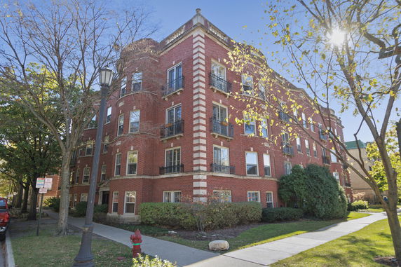 Front view of a multi-story red brick building with decorative windows and balconies.