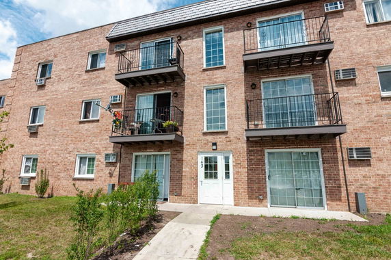 Front view of a multi-story brick building with balconies and large windows.