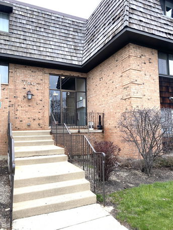 Front view of a two-story brick building with an entryway and steps.