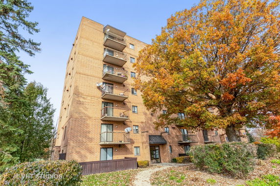 Front view of a multi-story brick apartment building with balconies.