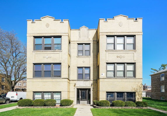 Front view of a three-story brick building with multiple windows.