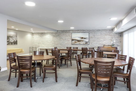 Interior of a recreation room with round tables and chairs.