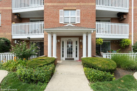 Front view of a multi-story brick building with balconies and white railings.
