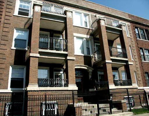 Front view of a multi-story brick apartment building with balconies.