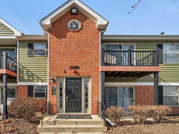 Front view of a two-story house with red brick facade and a black door.