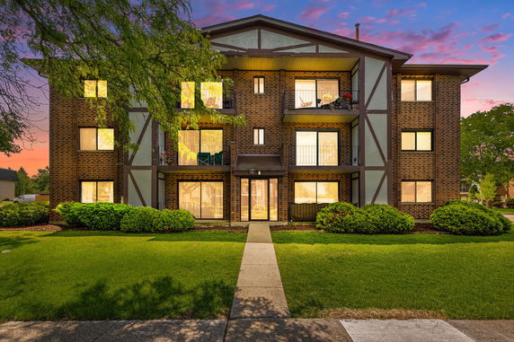 Front view of a multi-story apartment building with brick exterior and balconies.