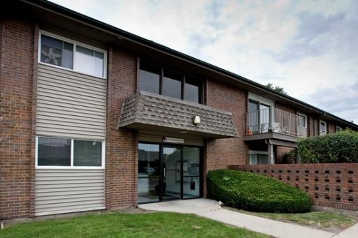 Front view of a two-story building with brick and siding exterior, featuring a main entrance with glass doors.