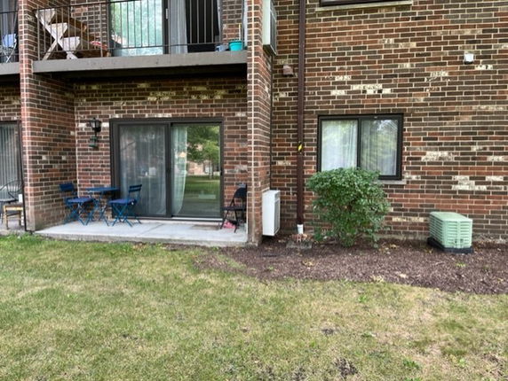 Front view of a brick building with a small outdoor seating area and sliding glass door.