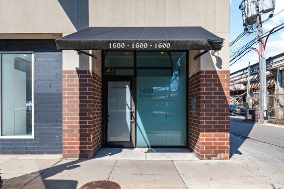 Front view of a building entrance with brick and glass facade, featuring an awning displaying the number 1600.