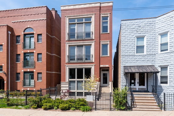 Front view of a multi-story brick building with large windows and a small front yard.