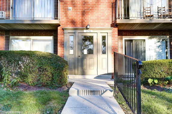 Front view of a brick building entrance with double doors and balconies above.