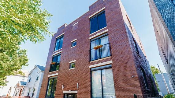 Front view of a multi-story brick apartment building with large windows and balconies.
