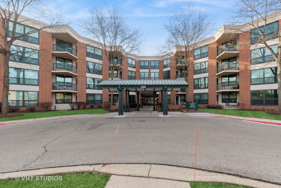 Front view of a multi-story apartment building with a central entrance and covered walkway.