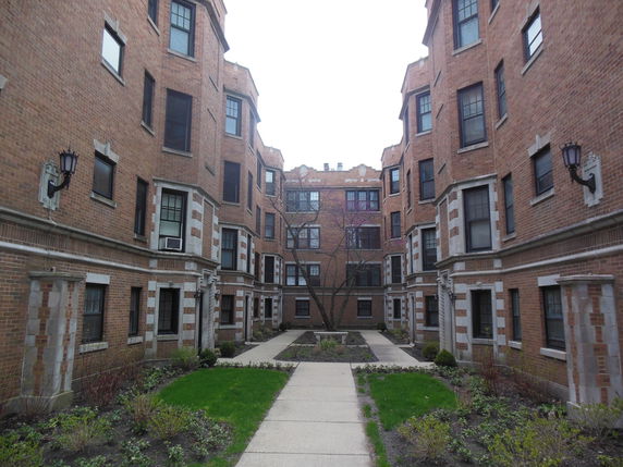 Front view of a multi-story apartment building with brick facade and multiple windows.