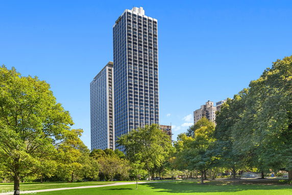 Tall residential building with a grid-like window pattern and adjacent structure.