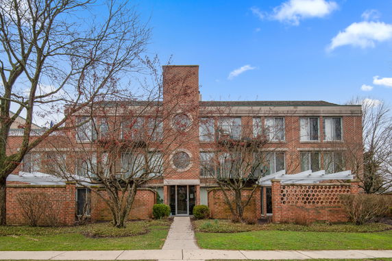 Front view of a three-story brick building with circle windows and a central entrance.